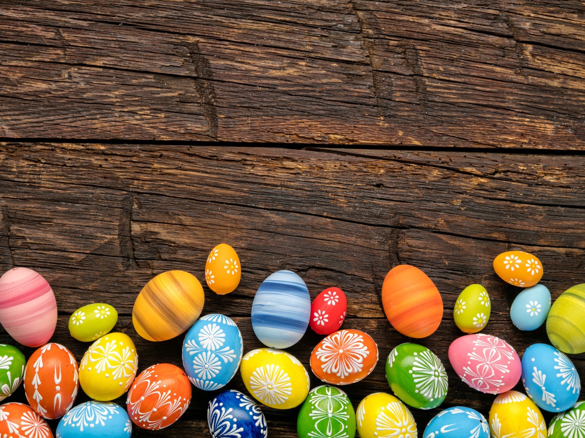 Разноцветные пасхальные яйца на деревянном столе