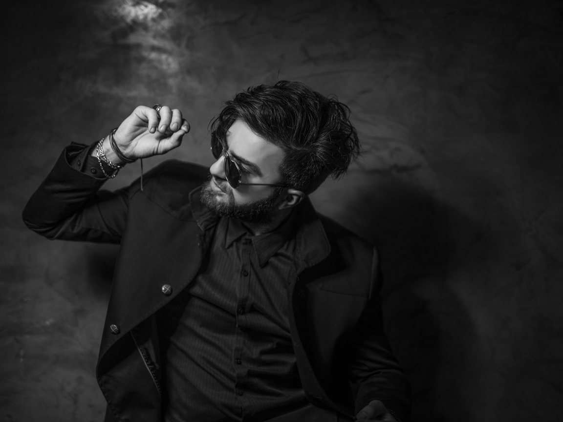 Мужчина в черном костюме на фоне стены