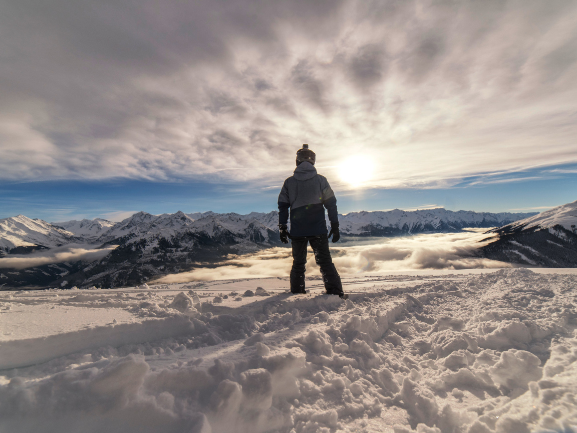 Человек в заснеженных горах в лучах солнца