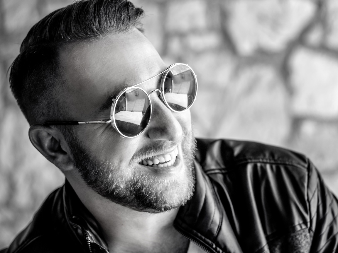 Улыбающийся брутальный мужчина в черных очках