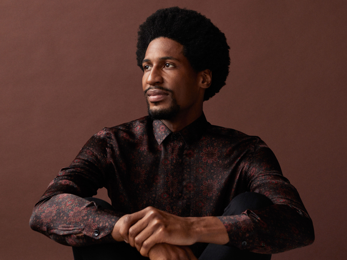 Музыкант Джонатан Батисте на коричневом фоне