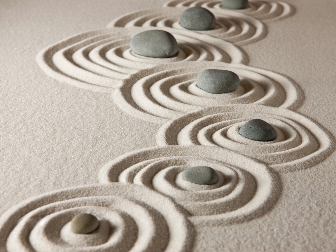 Маленькие серые камни с кругами на песке 