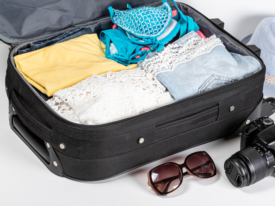 Чемодан с вещами для отпуска с фотоаппаратом и очками 