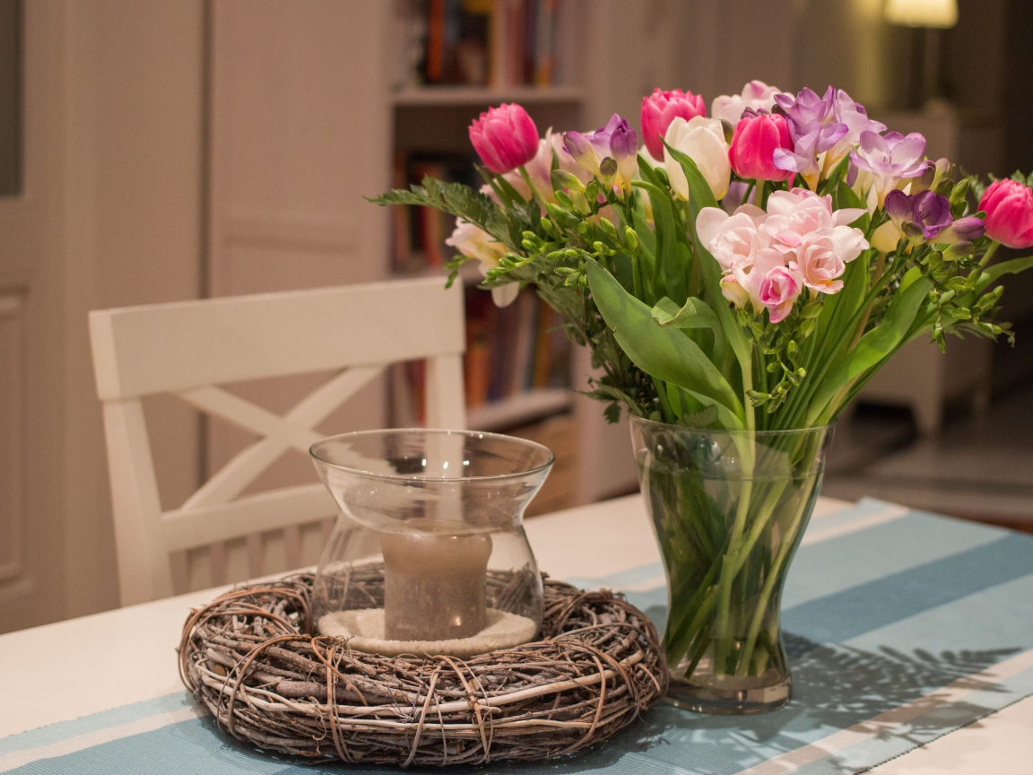 Красивый букет ярких цветов на столе со свечой