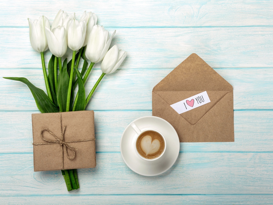 Bouquet of white tulips on a table with a gift and a cup of coffee