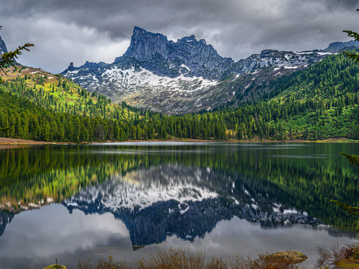 Красивая гора под грозовым небом отражается в озере 