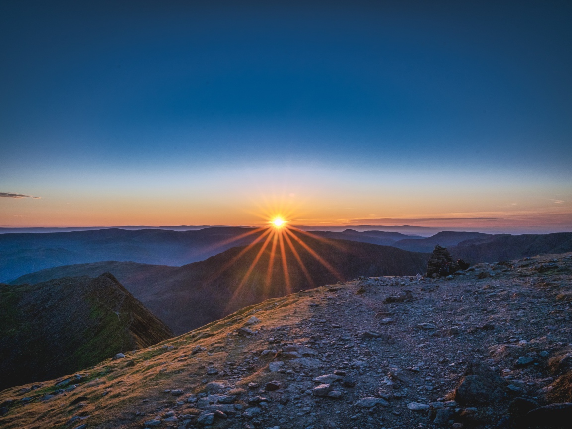 Рассвет яркого солнца в голубом небе над горами
