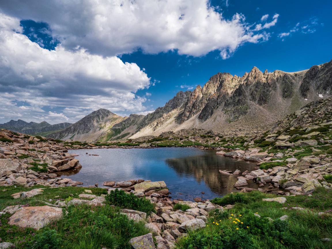 Горы под голубым небом с белыми облаками у озера, Андорра 