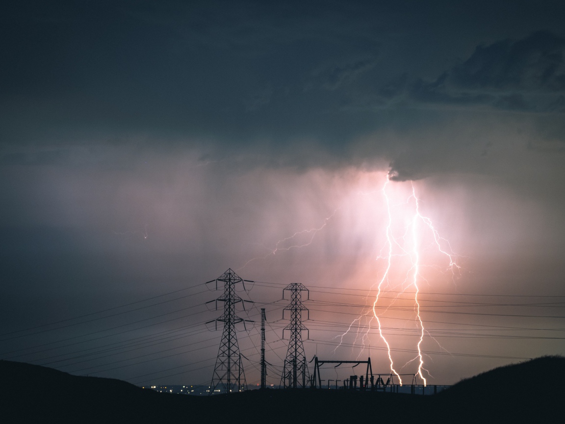 Яркая молния в небе над высоковольтной линией 