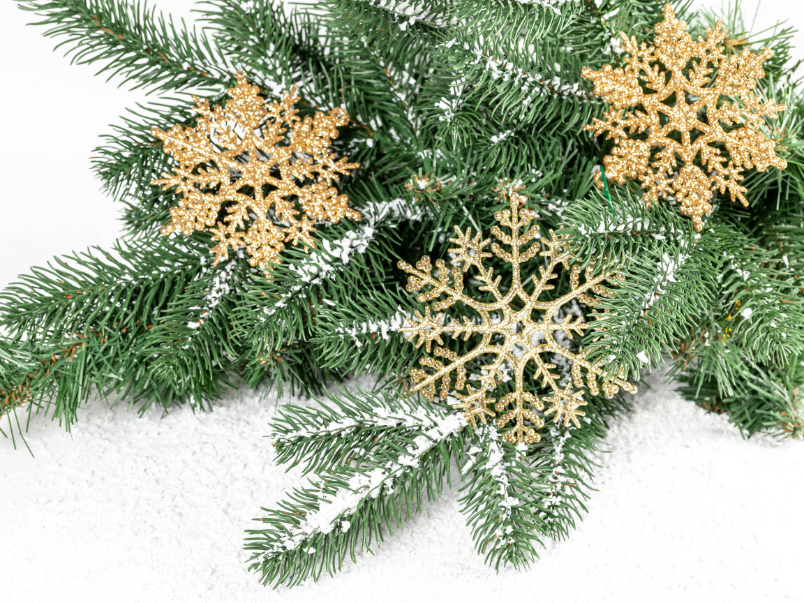 Золотистые снежинки и еловые ветки на снегу