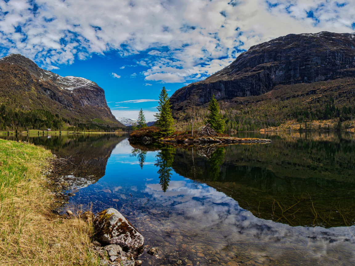 Остров среди озера у гор под красивым небом 