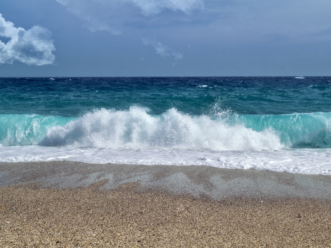 Голубые волны океана на мокром песке 