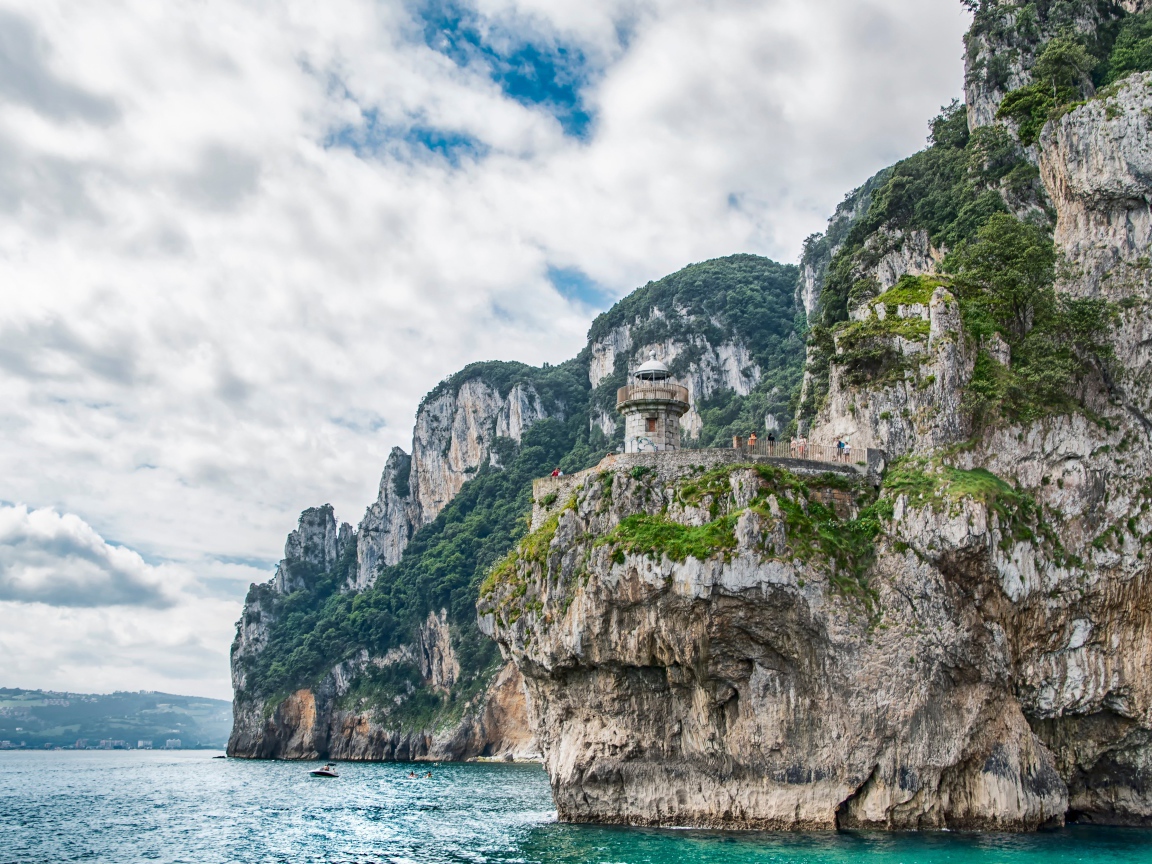 Высокие скалы у моря под белыми облаками 