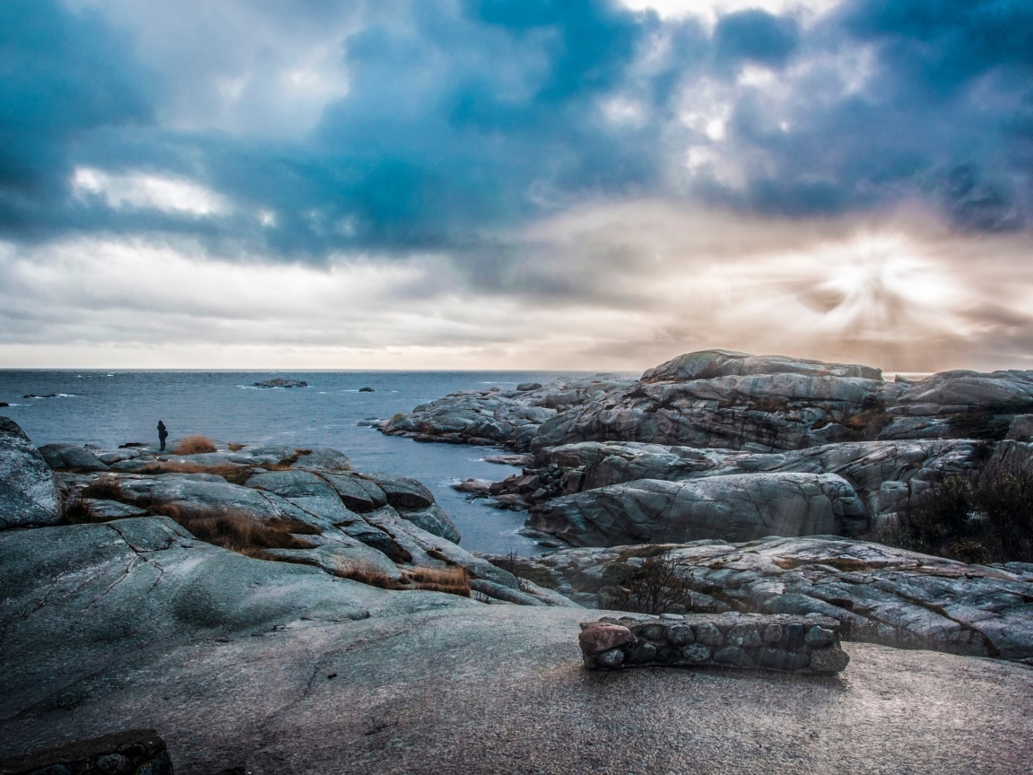 Каменный берег у тихого моря под черными облаками