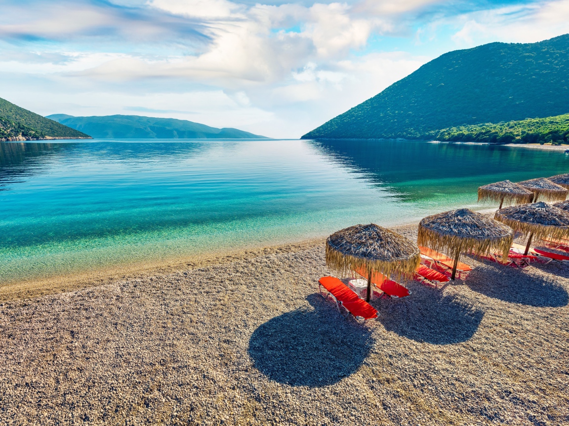 Шезлонги стоят на берегу озера у гор 