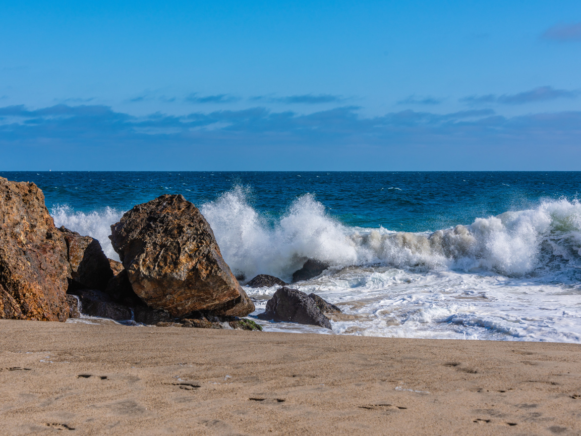 Белые морские волны бьются о большие камни на берегу