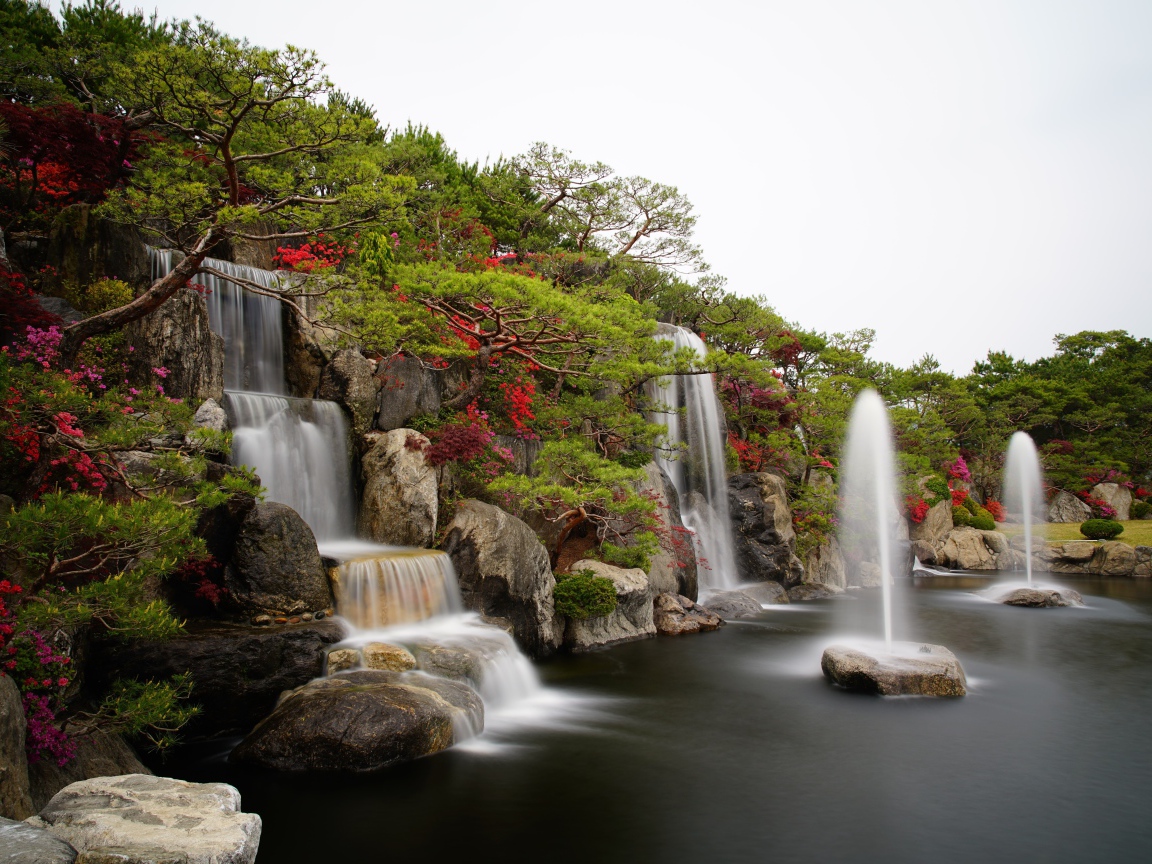 Водопады в красивом саду с зелеными деревьями