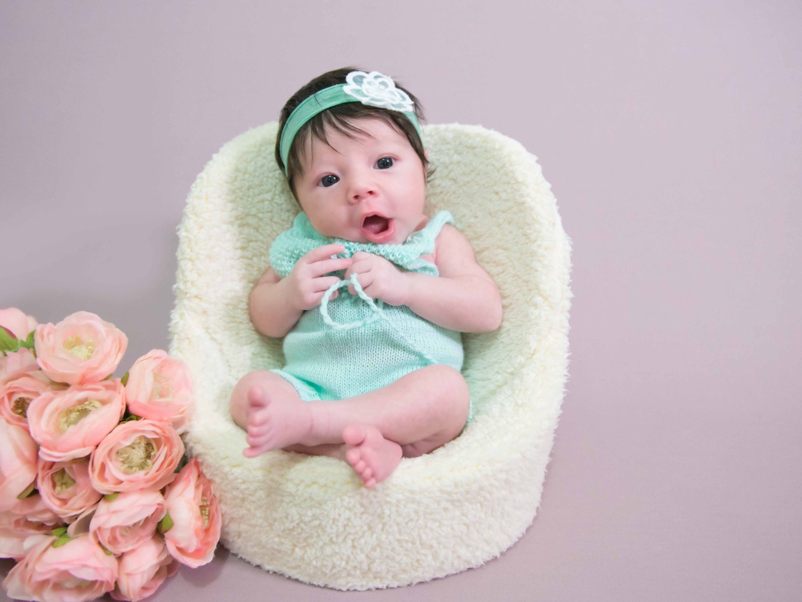 Милая малышка в кресле с букетом цветов