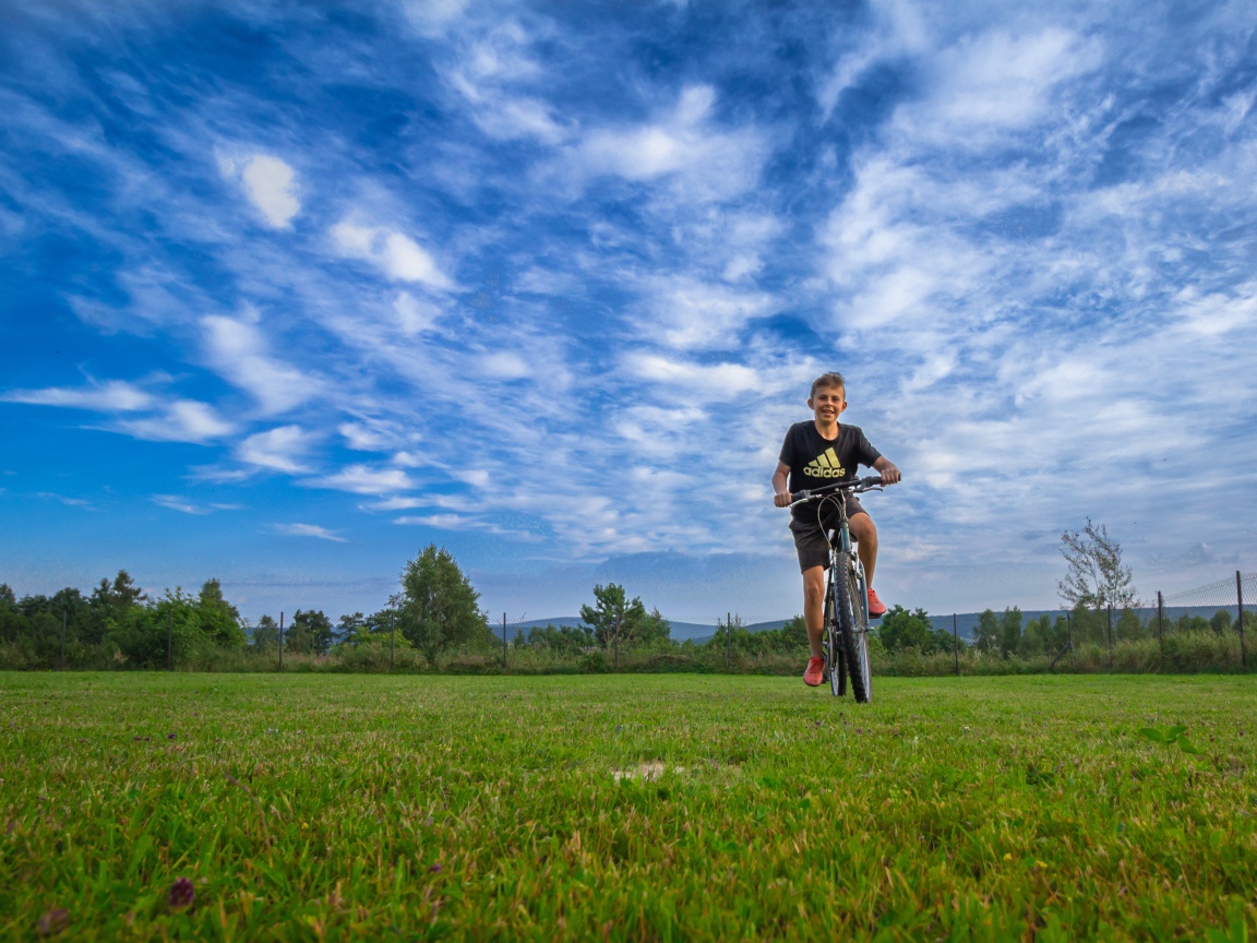 Маленький мальчик катается на велосипеде по полю 