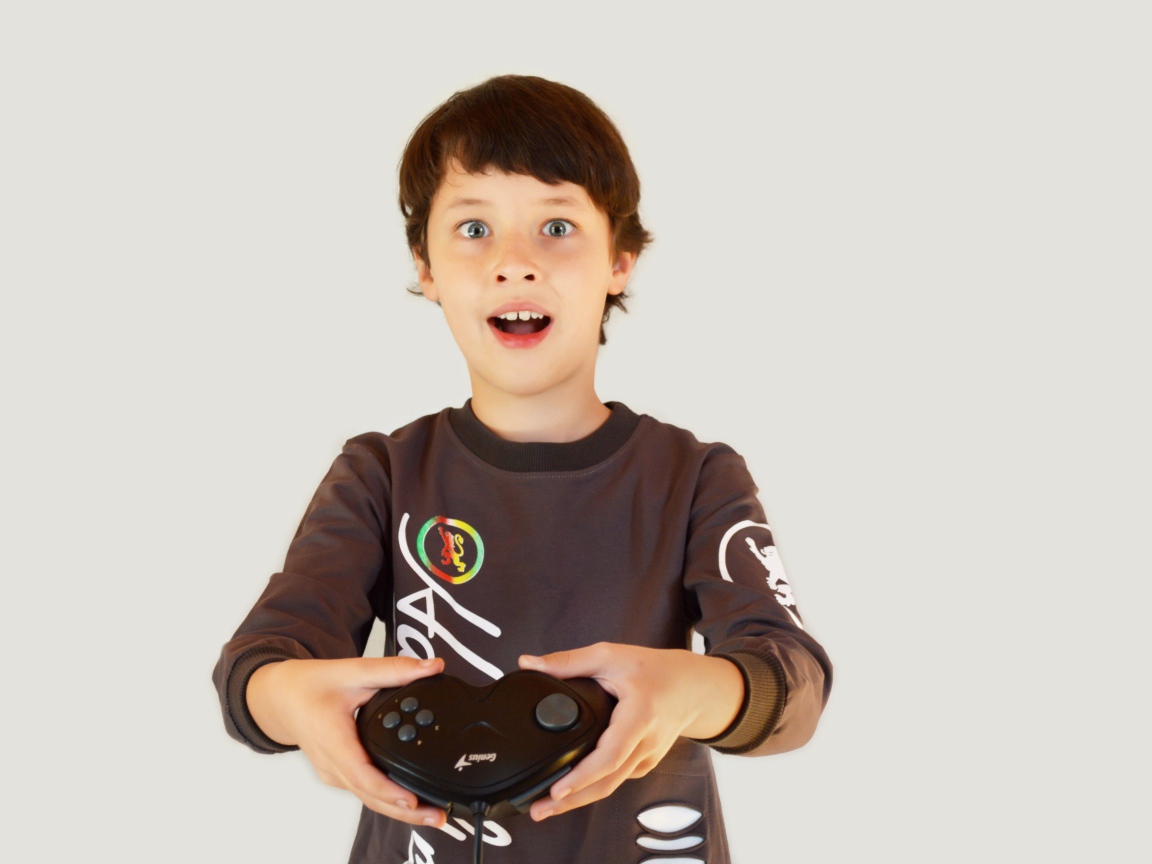 Маленький мальчик с приставкой на сером фоне 
