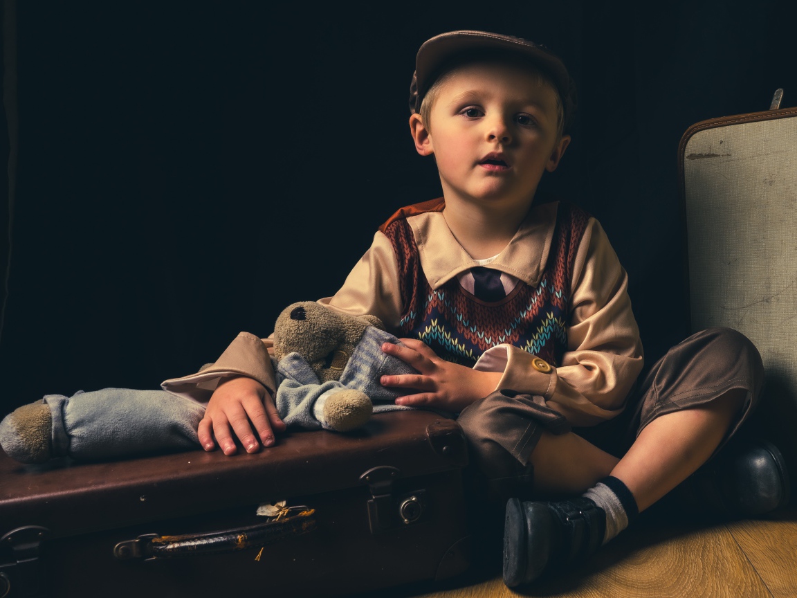 Маленький мальчик с чемоданом и игрушкой