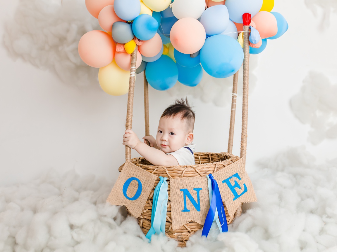 Маленький ребенок в корзине с шариками 