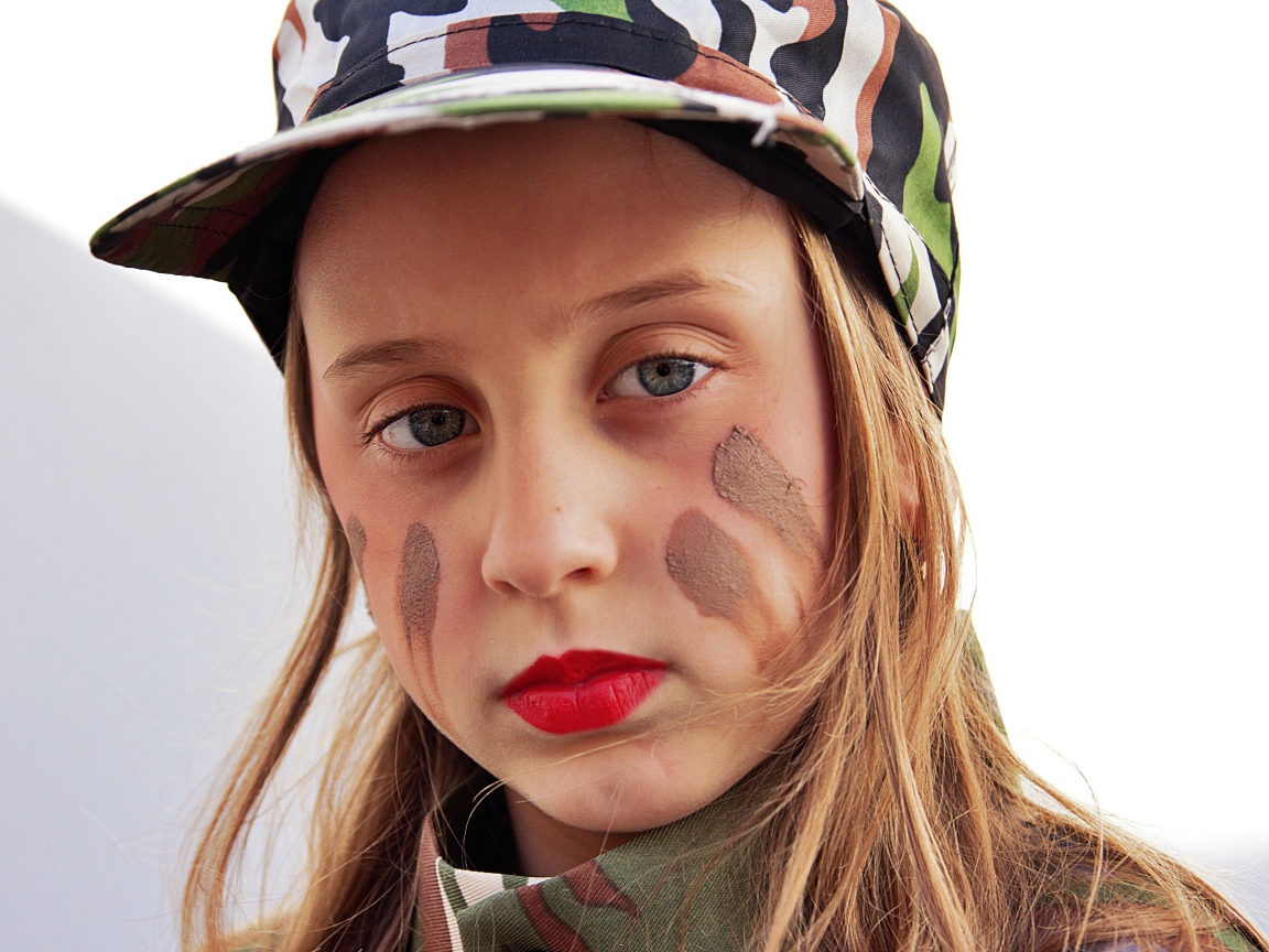 Маленькая девочка в кепке с грязью на лице