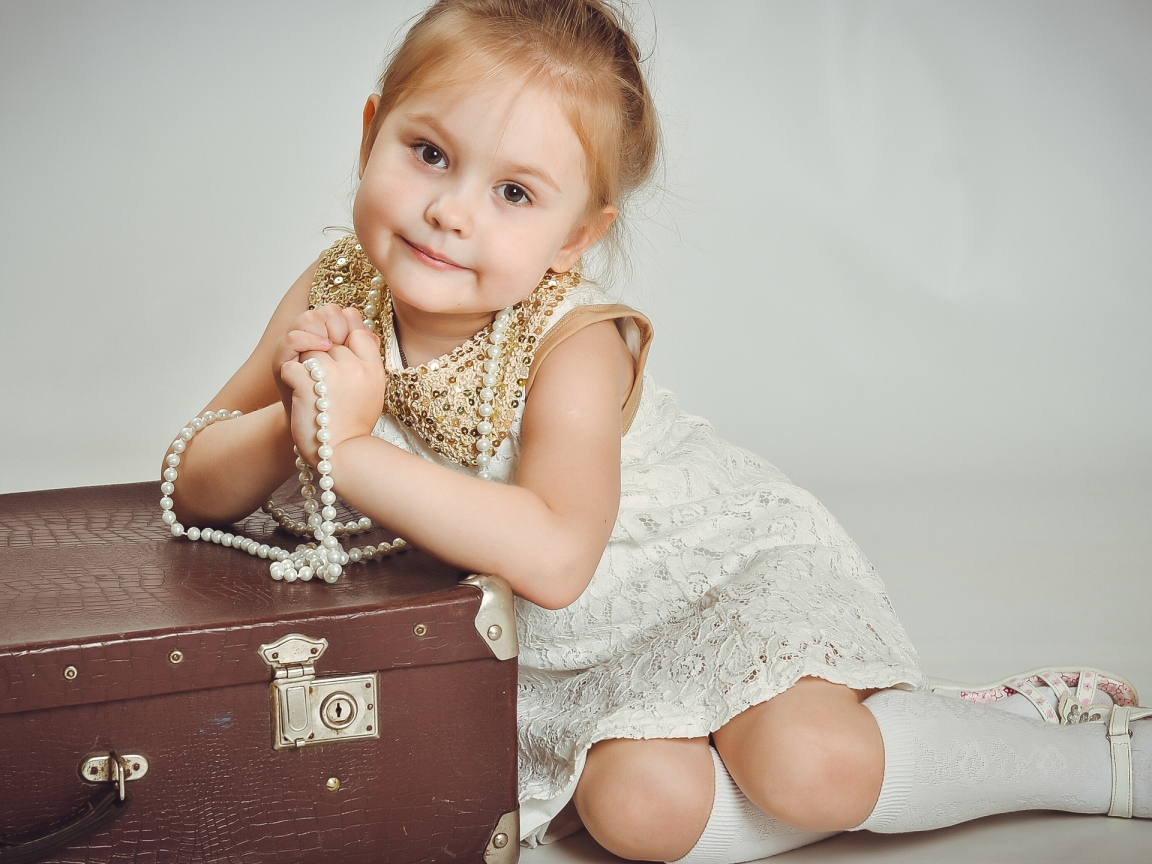 Маленькая девочка в белом платье с чемоданом