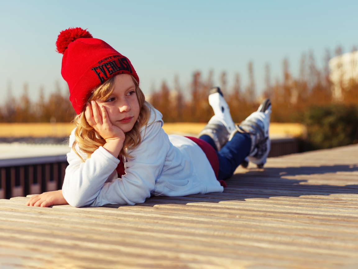 Маленькая девочка лежит на деревянном полу 