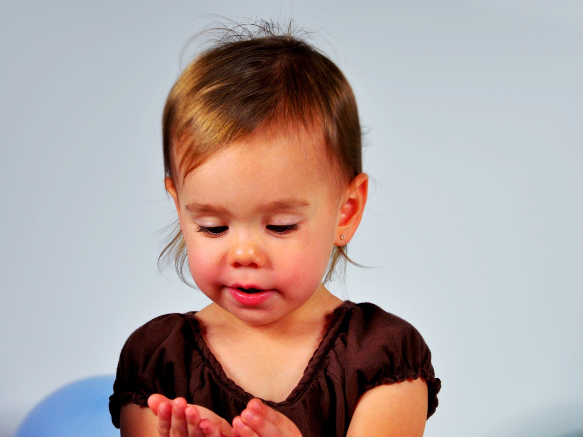 Маленькая девочка смотрит на руки на сером 