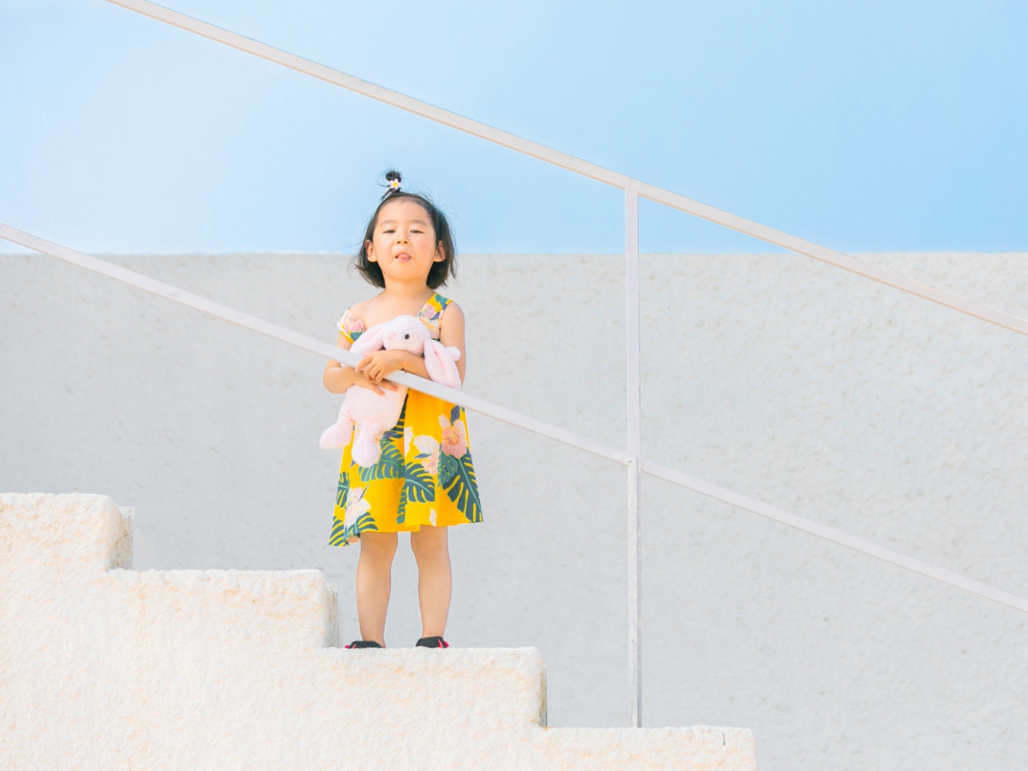 Маленькая девочка с игрушкой на ступеньках 