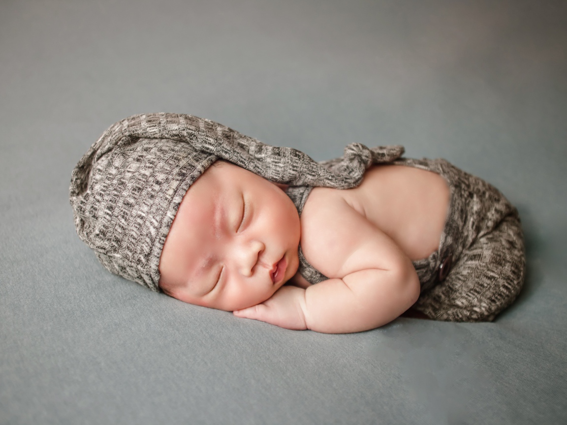 Маленький новорожденный ребенок на сером фоне