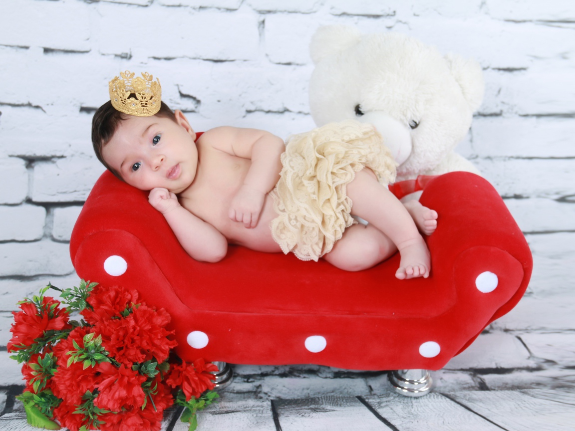 Маленькая принцесса лежит на красном диване у стены 