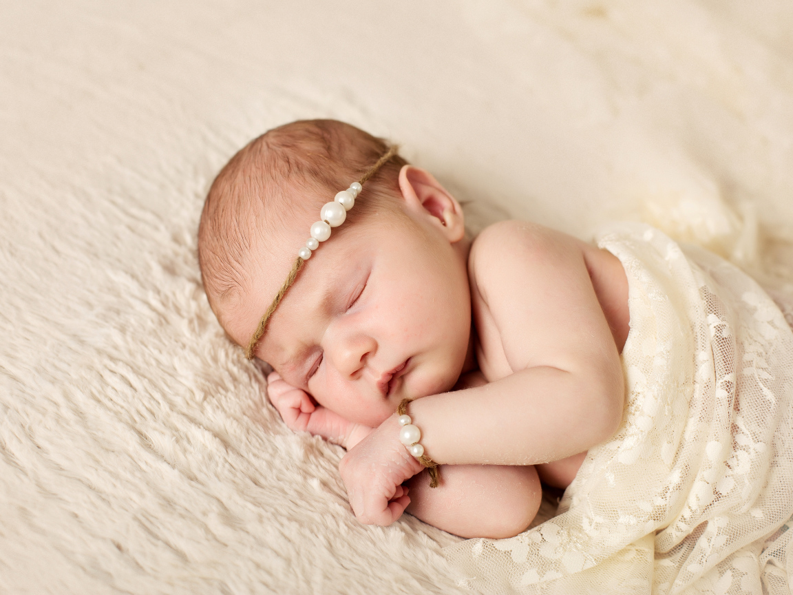 Спящий грудной ребенок с украшением с жемчугом на голове 