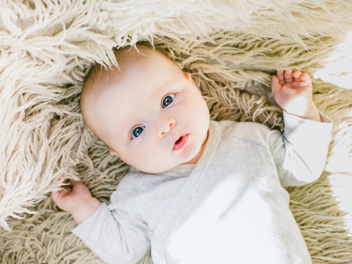 Маленький грудной ребенок на меховом покрывале 