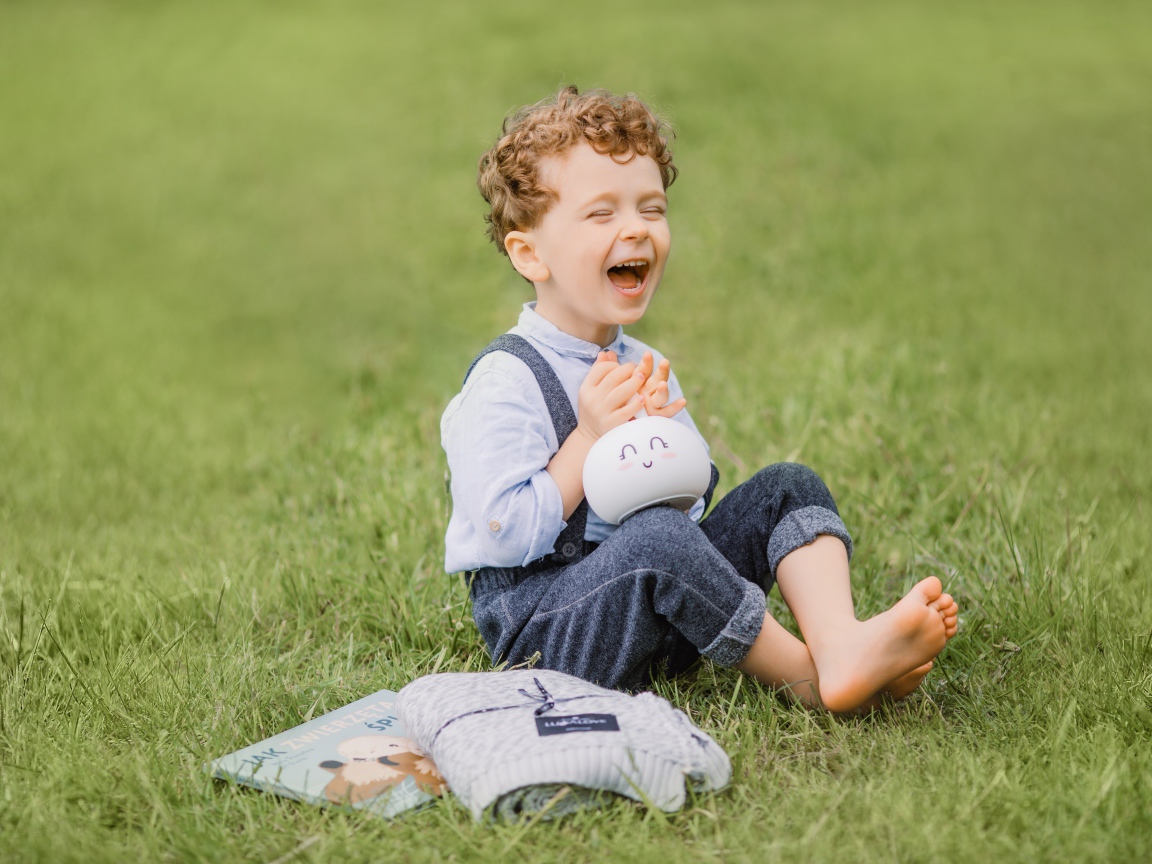 Улыбающийся мальчик сидит на траве