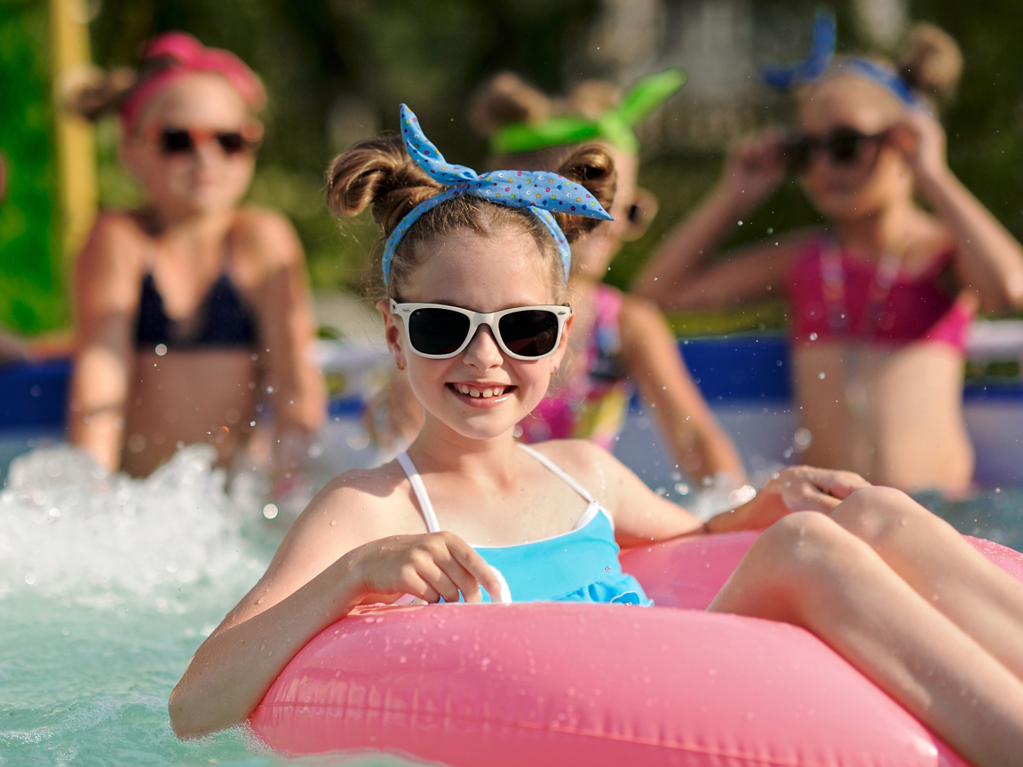 Улыбающаяся девочка со спасательным кругом в бассейне 