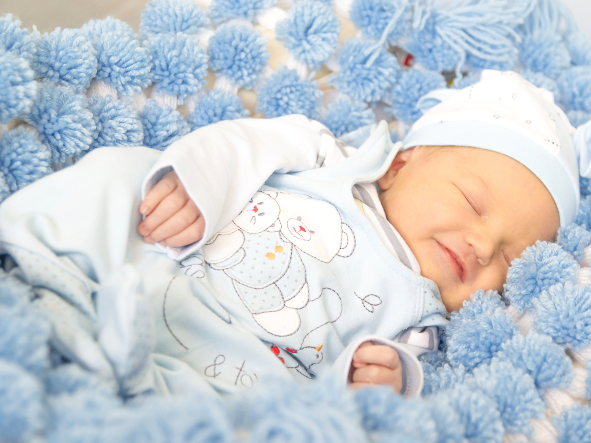 Улыбающийся грудной ребенок спит на голубом покрывале