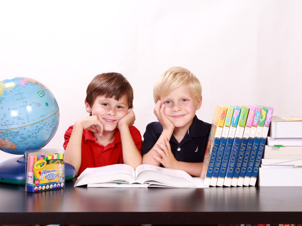 Два школьника за партой с книгами и глобусом 