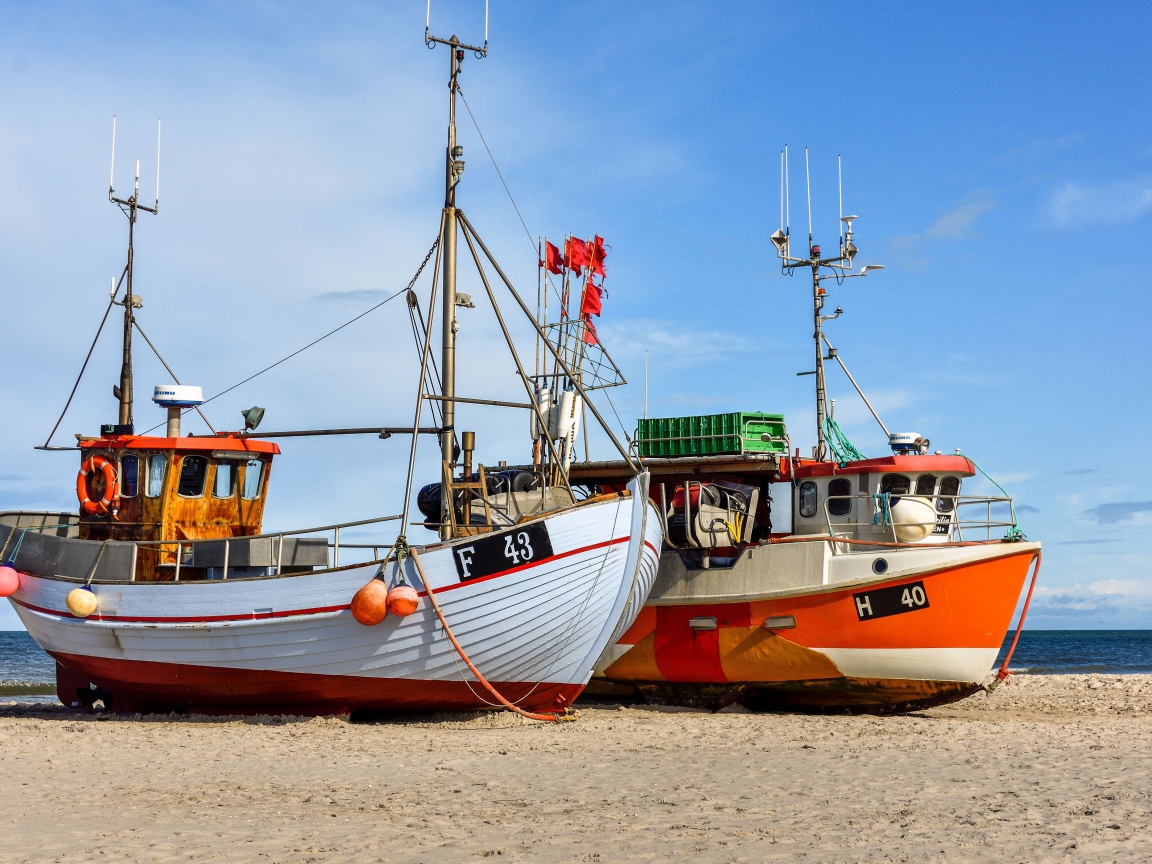 Две рыбацкие лодки стоят на песке у моря 