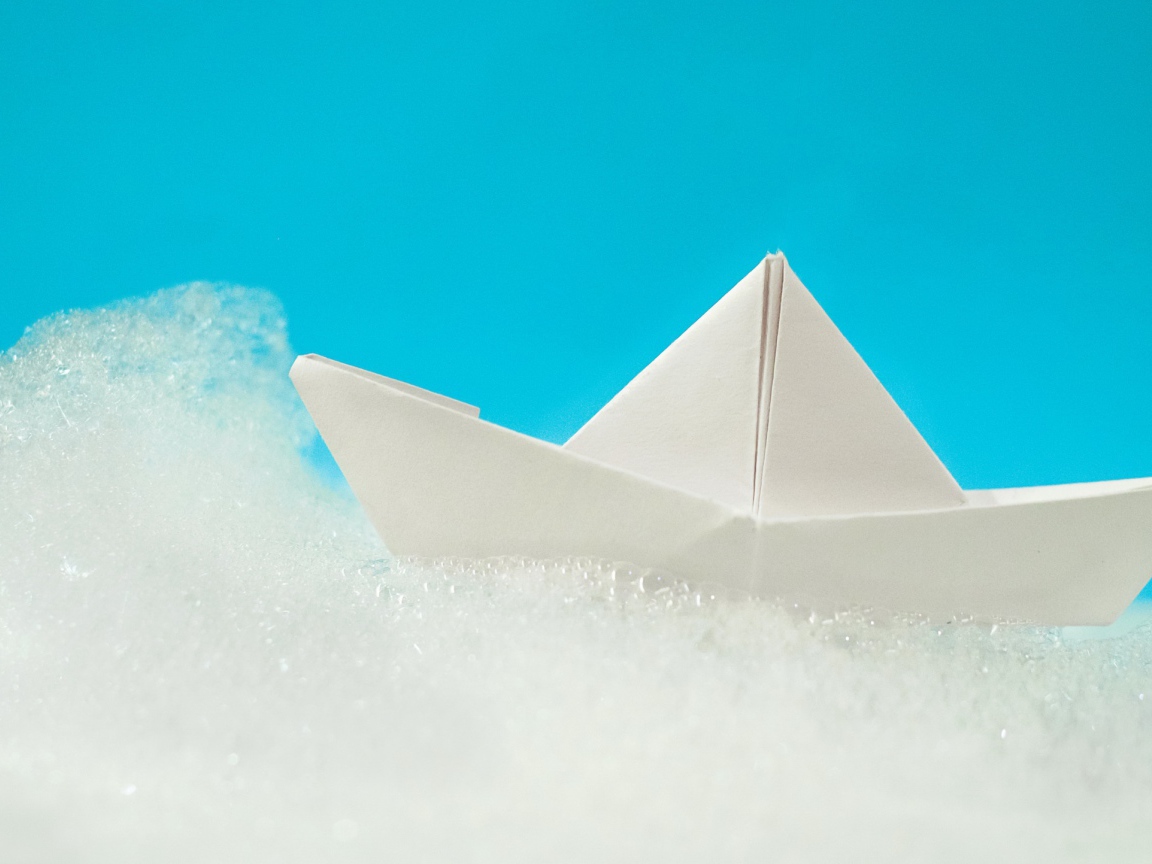 Белый бумажный кораблик на пене на голубом фоне