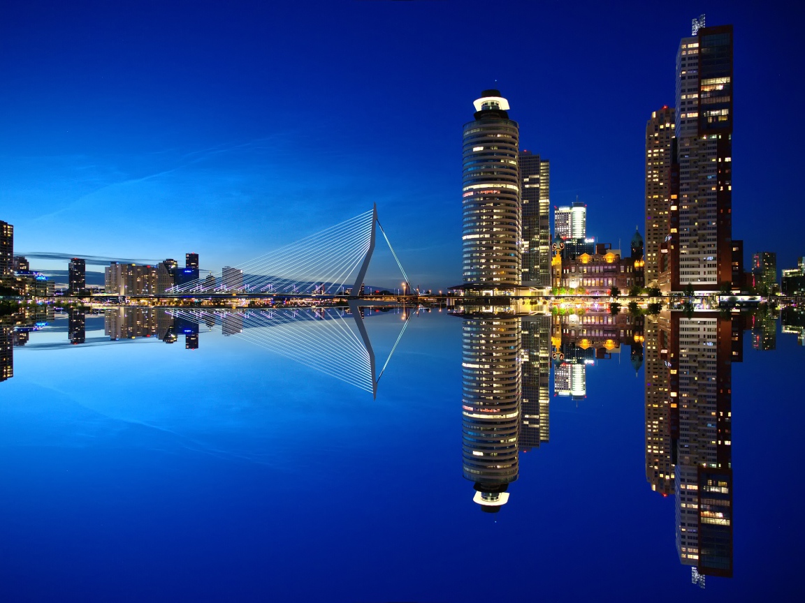 Небоскребы и мост отражаются в тихой воде