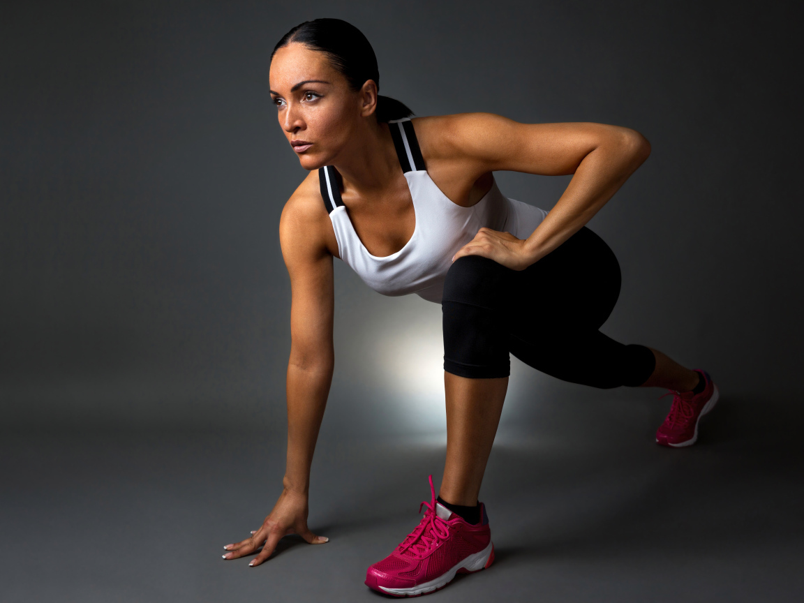 Девушка спортсменка в стойке на сером фоне 