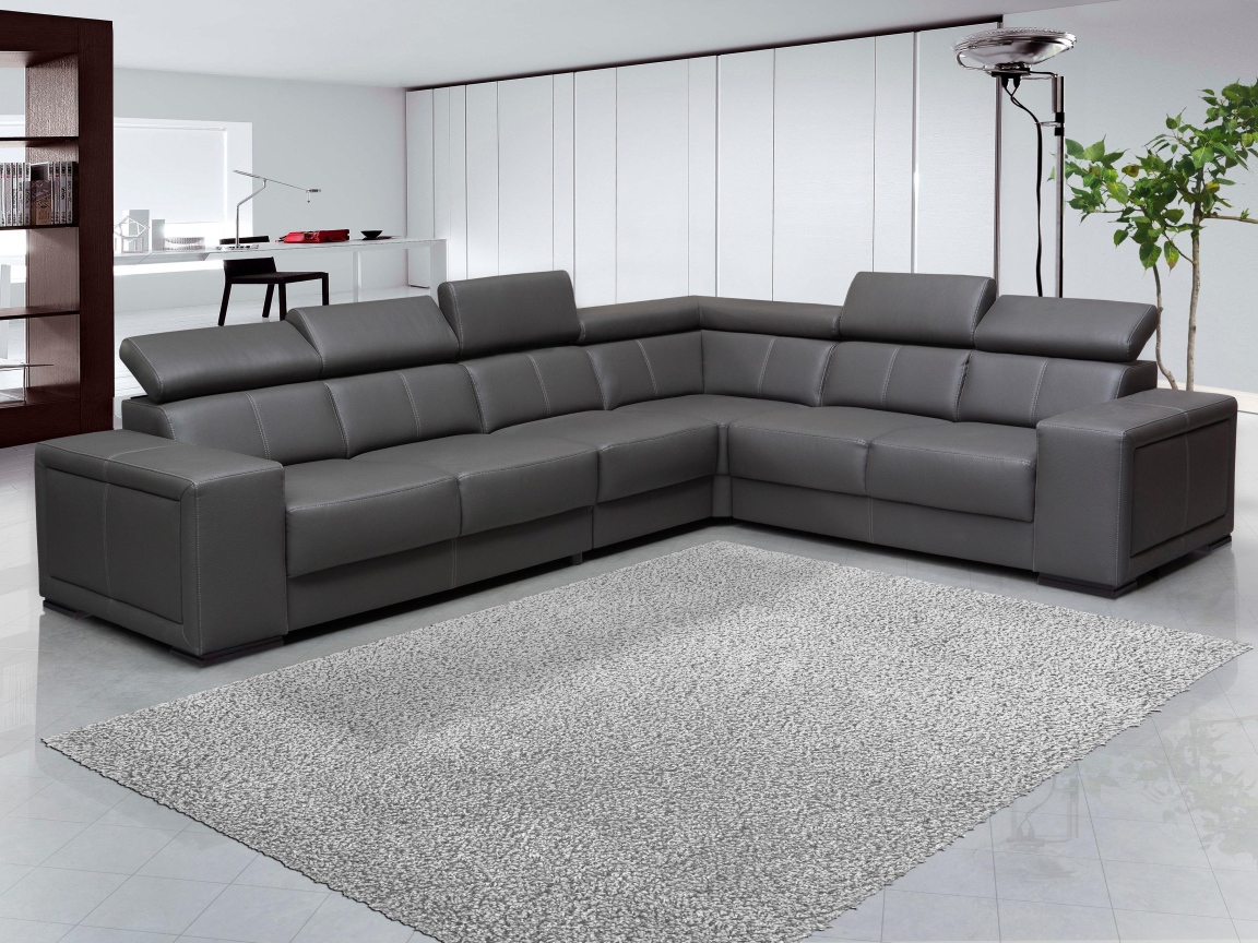 Большой черный угловой диван в комнате с белыми стенами