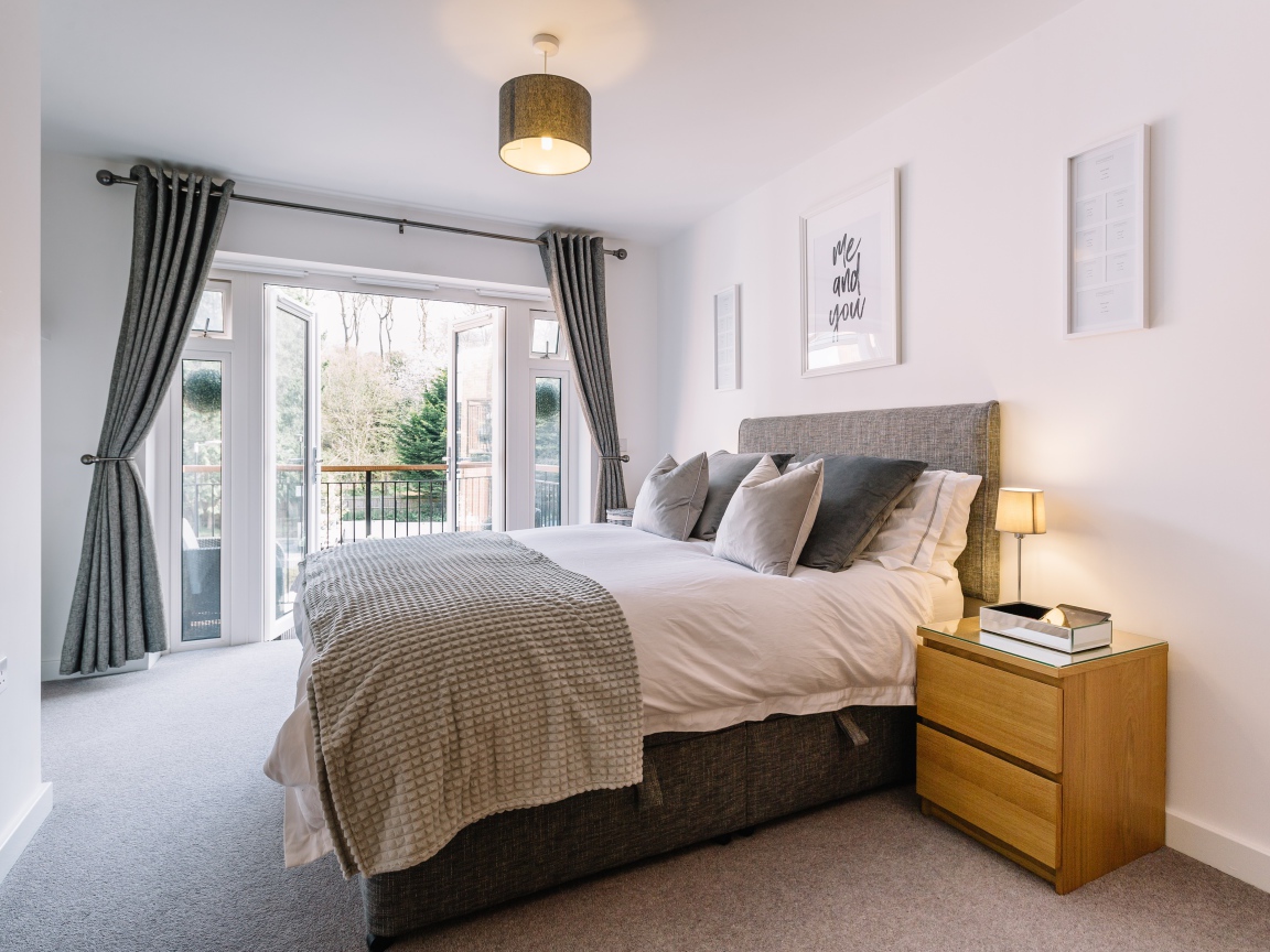 Большая высокая кровать в комнате с большим окном с балконом