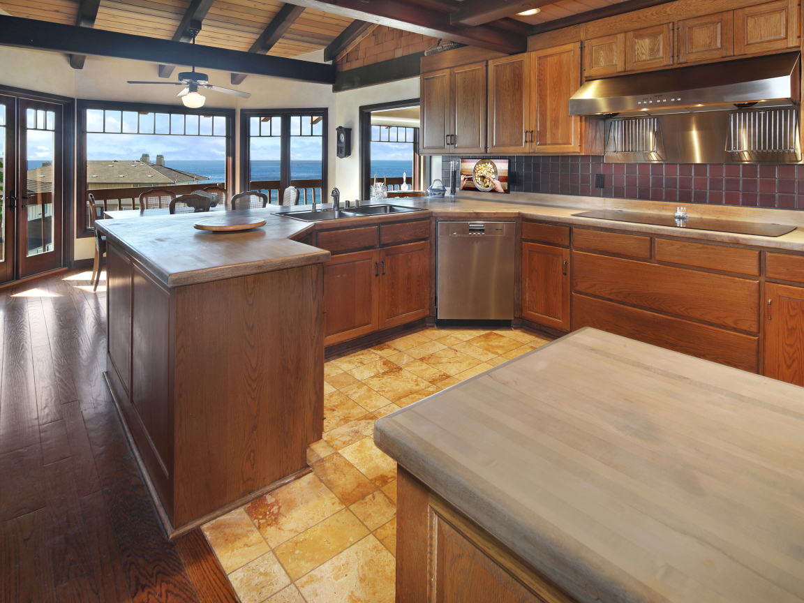 Деревянная мебель на кухне с окнами с видом на море