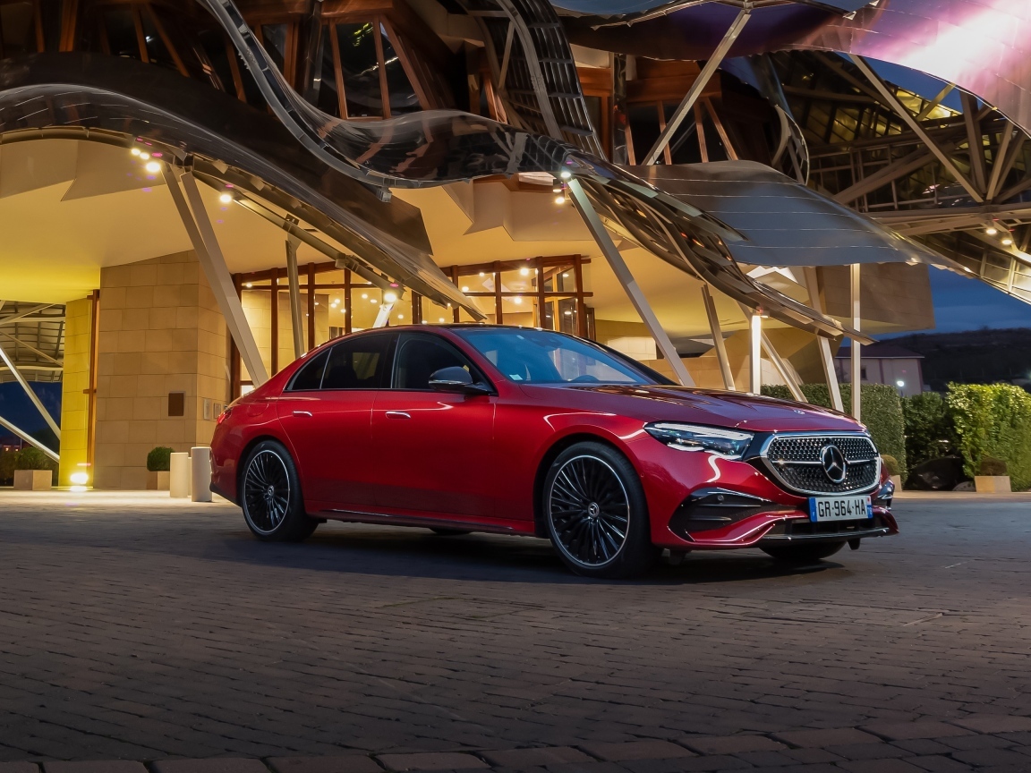 Красный автомобиль Mercedes-Benz E 220 D AMG Line у здания