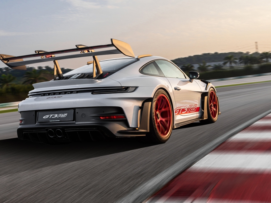 Серебристый спортивный автомобиль Porsche 911 GT3 RS Weissach Package 2023 года на трассе