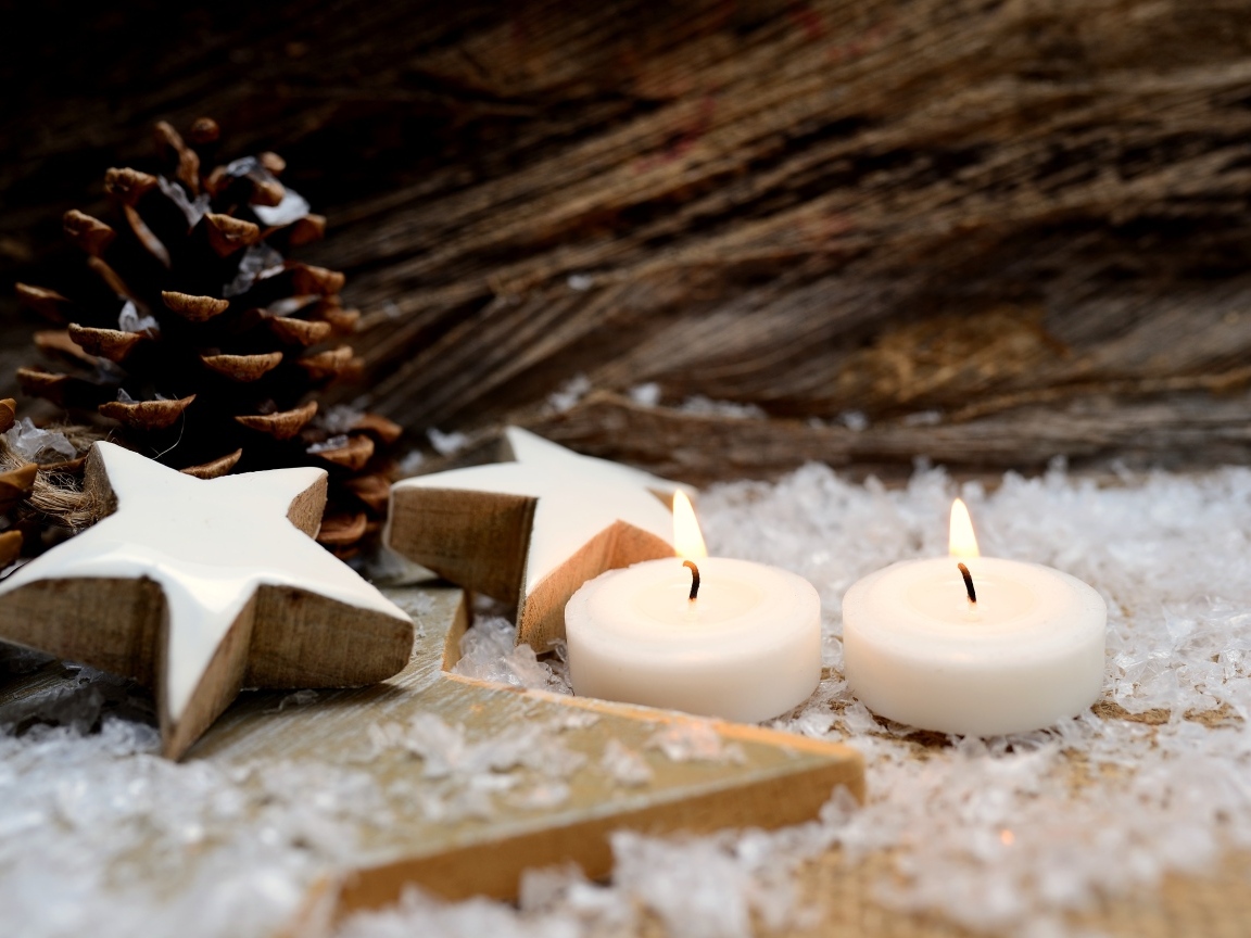 Две зажженные свечи, шишки и звезды