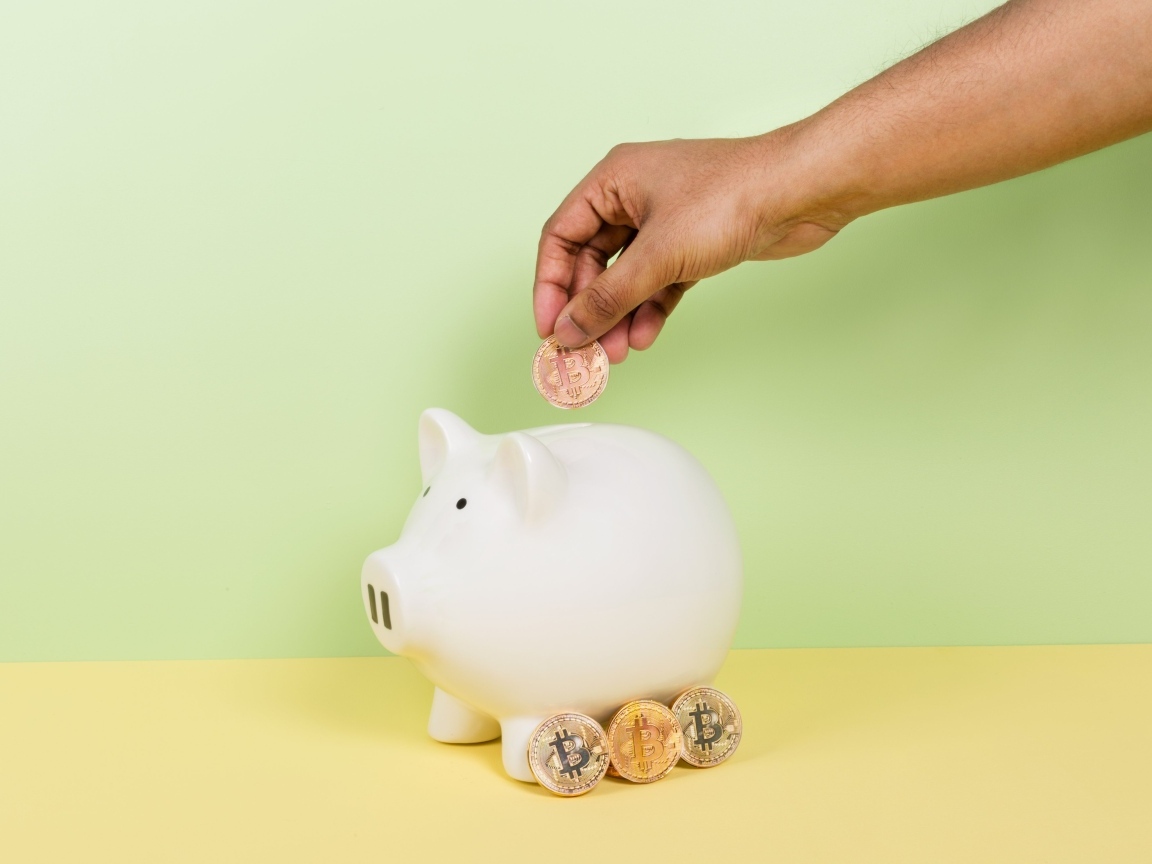 Рука бросает монету в свинью копилку